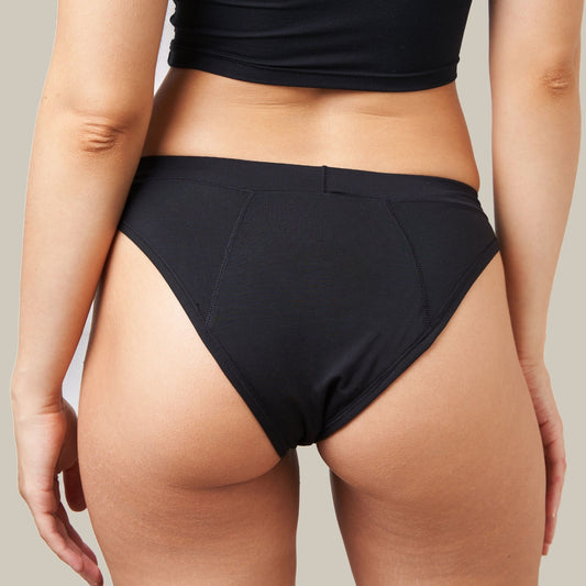 Juodos COMFORT BIKINI menstruacinės kelnaitės ant modelio, vaizdas iš nugaros