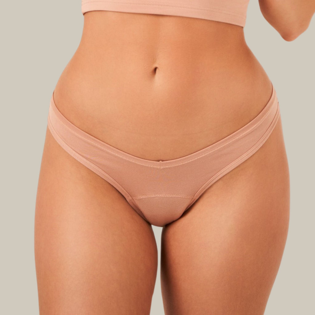 Kūno spalvos ACTIVE THONG menstruacinės kelnaitės ant modelio, vaizdas iš priekio